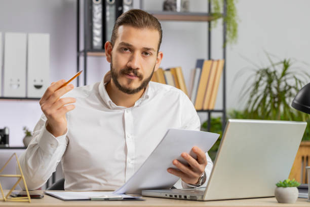 istock Business man reading business contract, planning project, analyzing resume, good paperwork results 1581536559