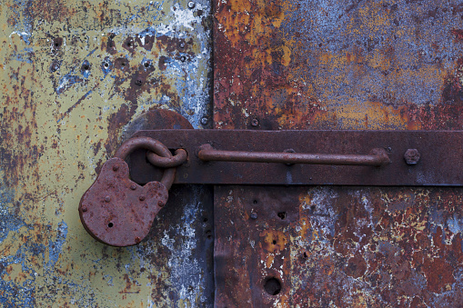 old rusty lock on the metal scratched door as a textured background