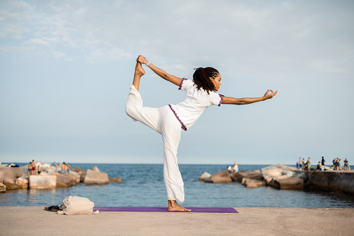 Young African American woman practicing yoga on the beach