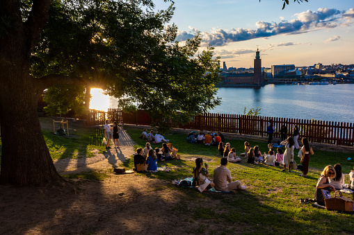 Stockholm, Sweden June 24, 2023 People sitting in the grass at sunset at Midsummer at the landmark Ivar Lo Park on Sodermalm.