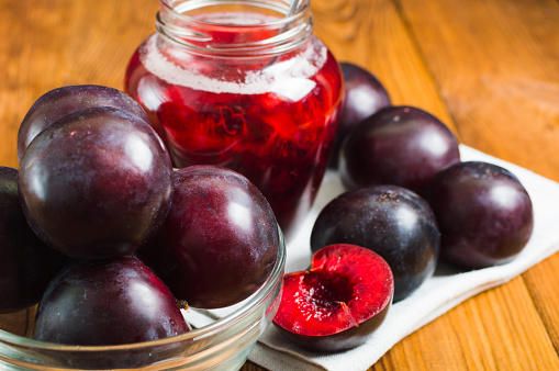Homemade plum jam with ripe plums on the wooden table