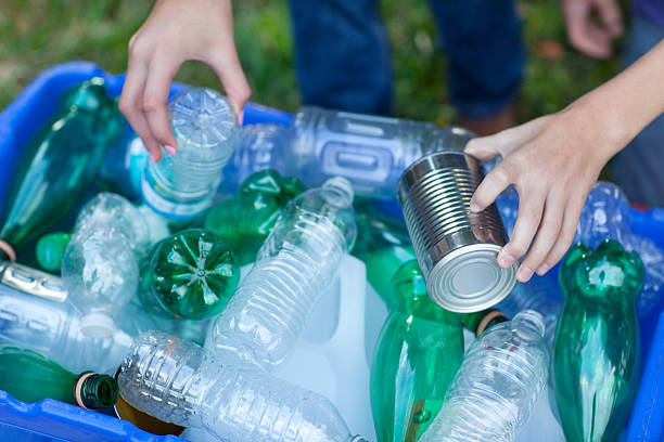 istock Hands placing rcans and bottles in recycling bin 158176453