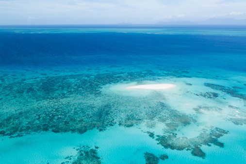 Aerial view of the Great Barrier Reef on clear sunny day with coral head atolls and natural reef patterns and boats. Queensland, Australia.