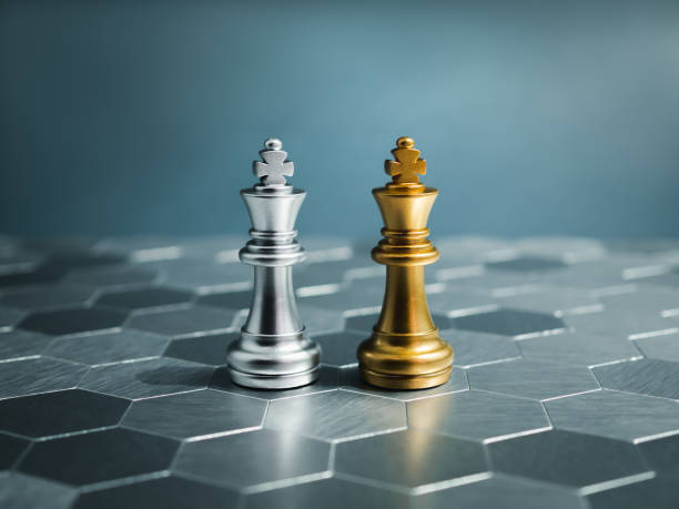 istock Golden and silver king, luxury chess pieces standing together on a silver hexagon pattern chessboard on blue background. Leader, friend, enemy, cooperation, partnership, and business strategy concept. 1581889500