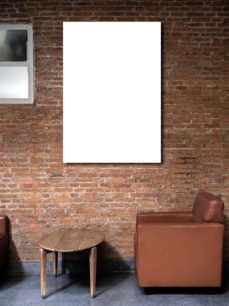 istock Mockup artist frame or white blank vertical poster on red brick wall background over the empty vintage brown single sofa seat, side view and wooden round side table inside the building loft style. 1581890010