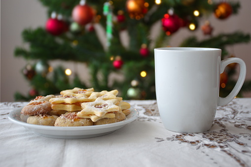 Cup of coffee and cookies on the table in front of Christmas tree
