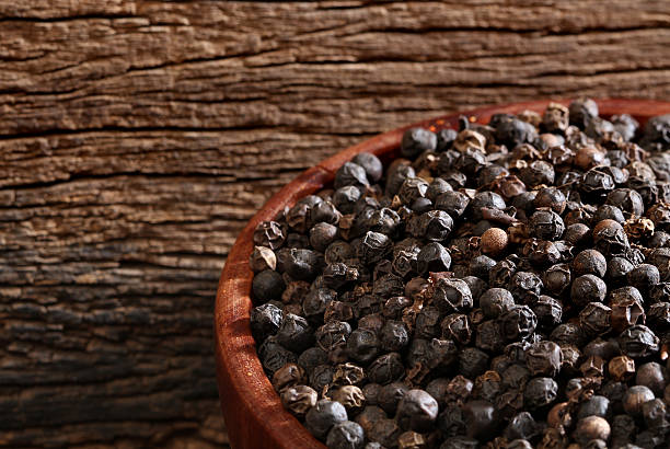 istock Bowl with black pepper over a wooden background 158194035