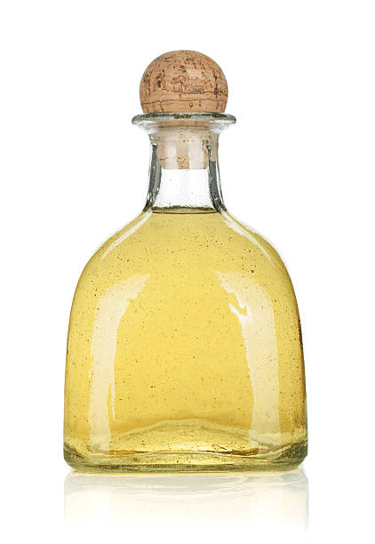 Unlabeled bottle of gold tequila on white background
