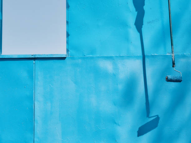 istock Shadow of paint roller on painted metal surface. Professional painting work. Blue background with copy space 1581965650