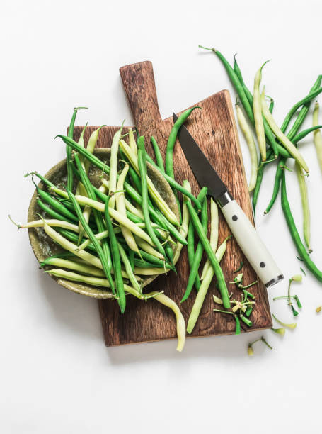 istock Green and yellow string beans on a wooden chopping board on a light background, top view 1581972745