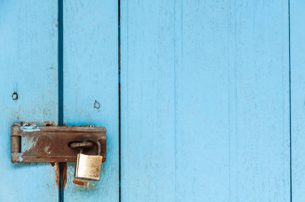 istock Old wooden door with rusty padlock and lock for background use 1582004751