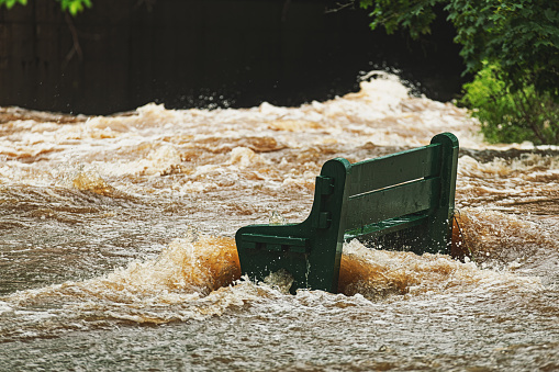 A park bench is overwhelmed by river flood water after record breaking rainfall.