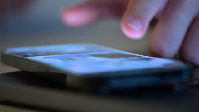 Close up of Woman scrolling on a mobile phone at home.