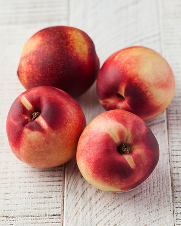 Ripe juicy nectarines on a white wooden background. The concept of stone fruits.