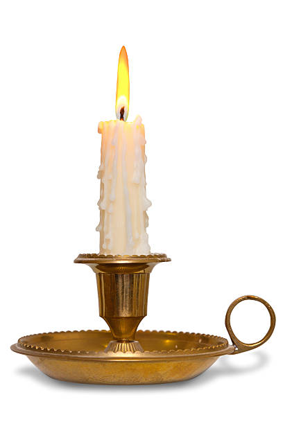 Candle in brass holder isolated A dripping wax candle burning with flame in a traditional brass holder known as a chamberstick, isolated on a white background. candlestick holder photos stock pictures, royalty-free photos & images