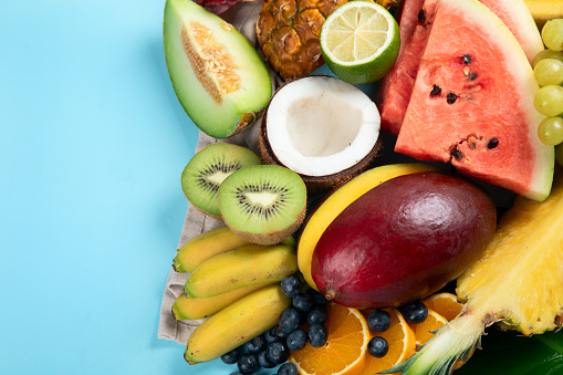 Fresh fruits assorted on a blue background. Vitamins natural nutrition concept. Top view. Copy space.
