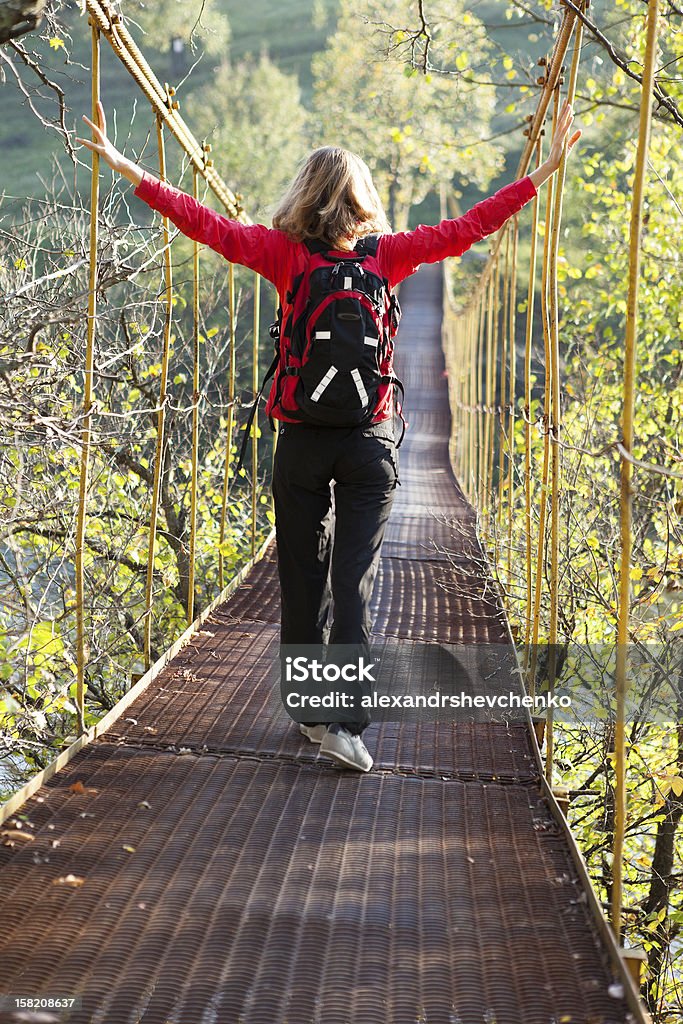 Mujer caminar en puente colgante con estirados para manos - Foto de stock de Actividad libre de derechos