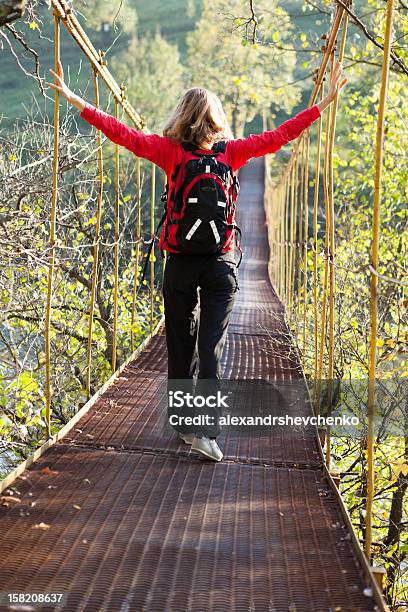 Mujer Caminar En Puente Colgante Con Estirados Para Manos Foto de stock y más banco de imágenes de Actividad