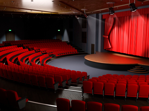 Modern theater hall / exhibition center with empty red seats and velvet stage curtain.