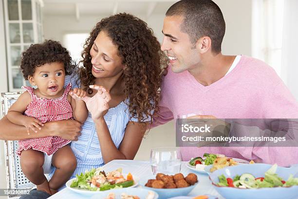 Familia Disfrutando De Una Comida Juntos En Casa Foto de stock y más banco de imágenes de 6-11 meses - 6-11 meses, Adulto, Adulto joven