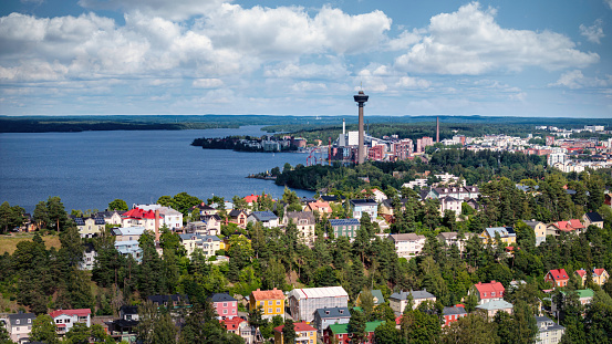 Tampere Cityscape in Summer under blue sky with fluffy clouds. Näsijärvi Lake Waterfront Tampere City View. Näsinneula Observation Tower in the background. Stitched DJI Mavic 3 Pro Photo. Tampere, Näsijärvi Lake, Finland, Nordic Countries, Scandinavia, Northern Europe