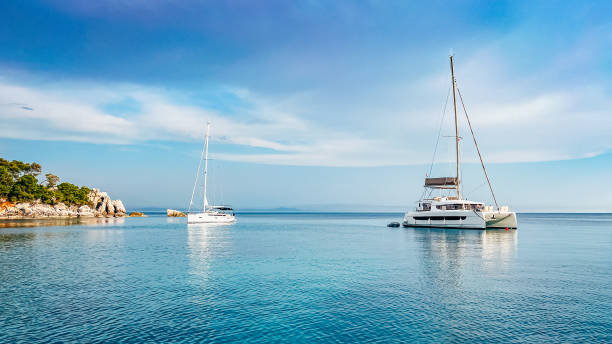 Anchored sailboat and catamaran stock photo