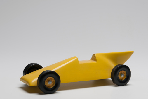 Studio shot yellow homemade toy race car used for the Boy Scouts Pinewood Derby competition.