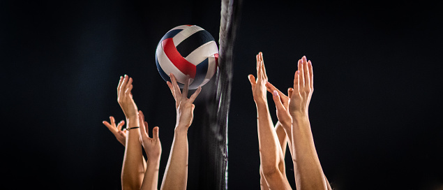Women volleyball players hands throwing volleyball ball during match.
