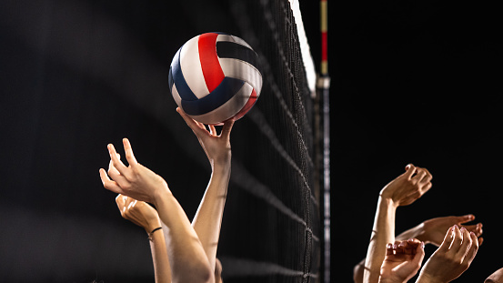 Close-up of women volleyball players hands throwing volleyball ball during match.