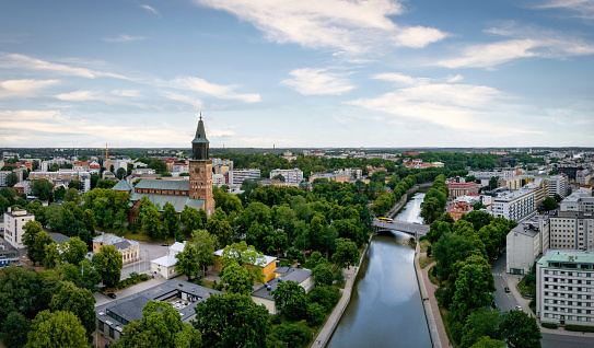 Finland Aura River in the City of Turku View with Turku Cathedral, Finnish Turun Tuomiokirkko in summer under blue sky. Scenic aerial drone point of view along the river bank and waterfront promenade of the River Aura with crossing bridges and the iconic Turku Cathedral on hill top close to the River Aura. Aura River Turku or Swedish: Åbo, Southwest Finland, Finland, Northern Europe, Nordic Countries