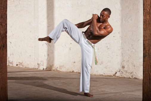 Young Black man demonstrating a knee kick indoors