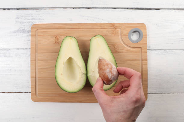 istock Avocado in a woman's hands. Bamboo cutting board 1582262666