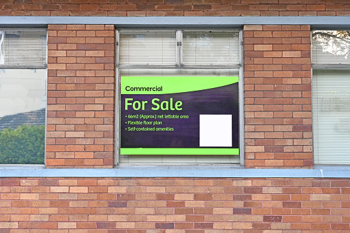 Commercial for sale sign in the window of a brick building