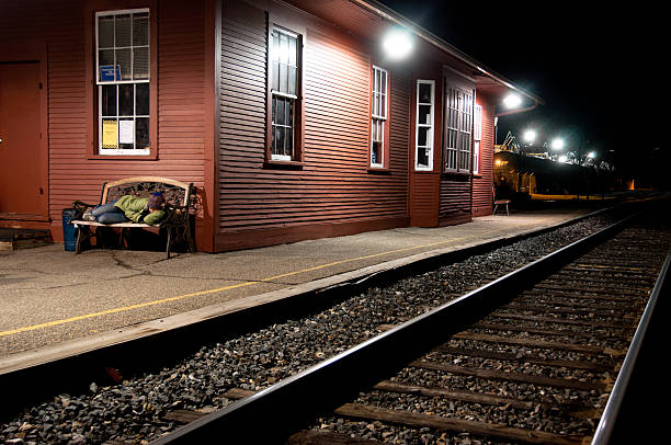 Sleeping on a train station bench at night stock photo