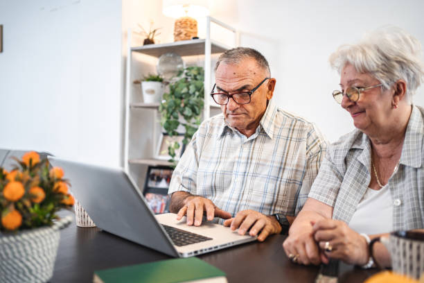 istock Affectionate married senior couple using laptop together at home 1582295286