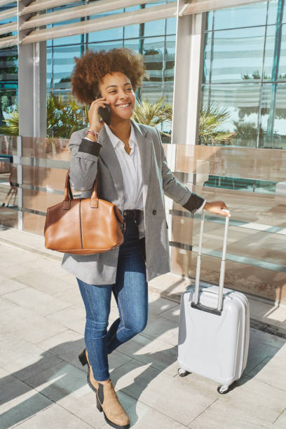 istock Black woman with suitcase talking on smartphone 1582315764