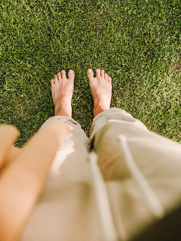 Closeup of bright flip flops and legs on green grass
