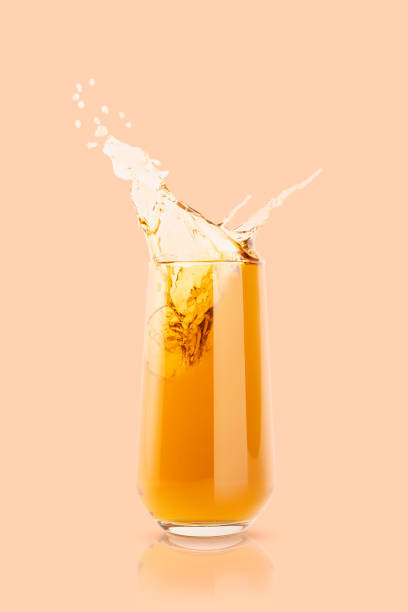 istock Apple yellow fresh juice in glass with reflection, drops and splashind pastel beige background, copy space, vertical. Vitamin organic gold summer drink with splashes, drops and motion in glass. 1582347708