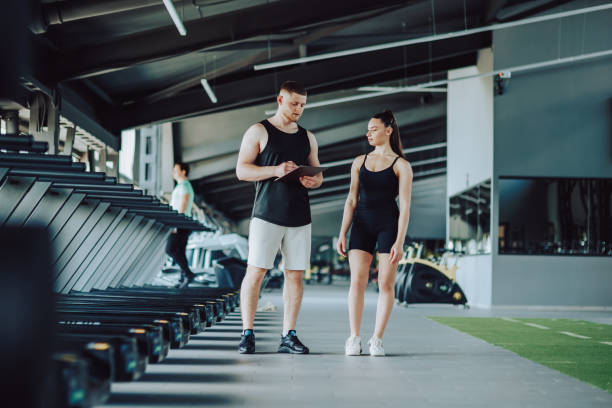 istock Discussion and Instruction Male Personal Trainer Talks to a Woman during Training 1582359148
