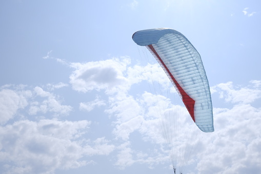 A paraglider in the blue sky. The sportsman flying on a paraglider.