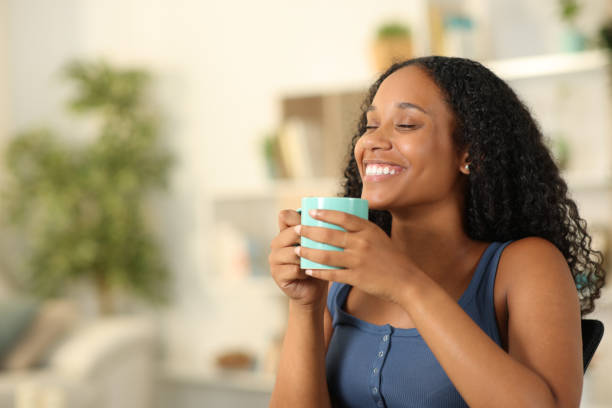 istock Happy black woman breathing drinking coffee at home 1582371874
