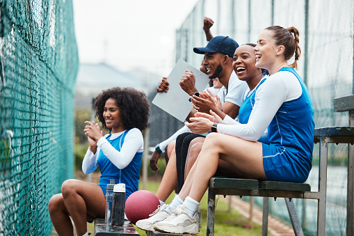 Court, netball and happy coach with women on stand watching game, match and practice on court. Coaching, teamwork and female athletes cheer for support, motivation and excited for sports competition