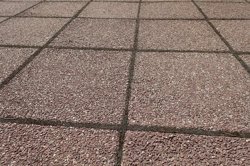 Coarse surface of pavement made of pink tiles of resin bound gravel