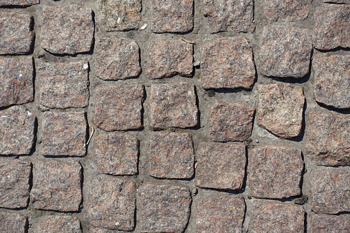 Close view of pavement made of rectangular pink granite stone setts