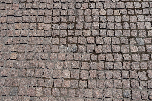 Surface of pavement made of rectangular pink granite stone setts