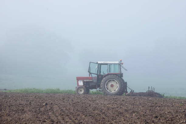 old abandones tractor in field with fog and trees in the background