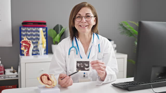 Middle age hispanic woman doctor showing ultrasound at clinic