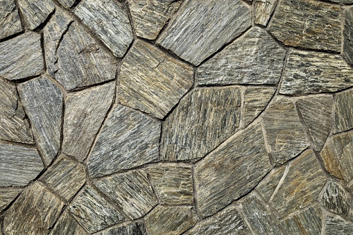 Natural stone wall coating with rocks of different sizes arranged geometrically. Background and texture.