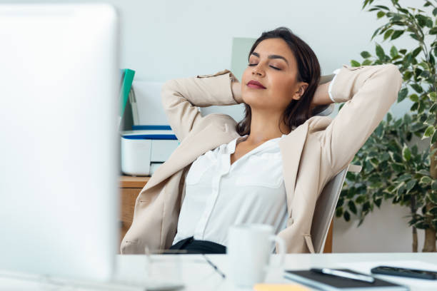istock Beautiful elegant business woman stretching while working on computer in the office 1582432786