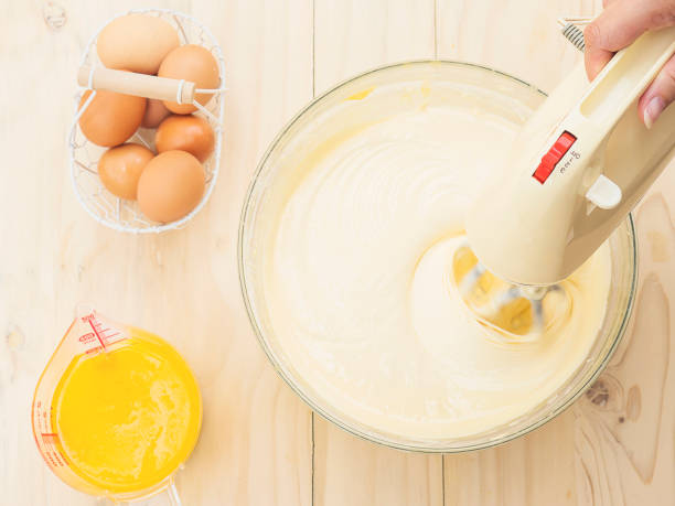 istock Lady's hand preparing cake using hand mixing machine with egg and butter 1582464095